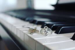 Music note ring and cross necklace on piano